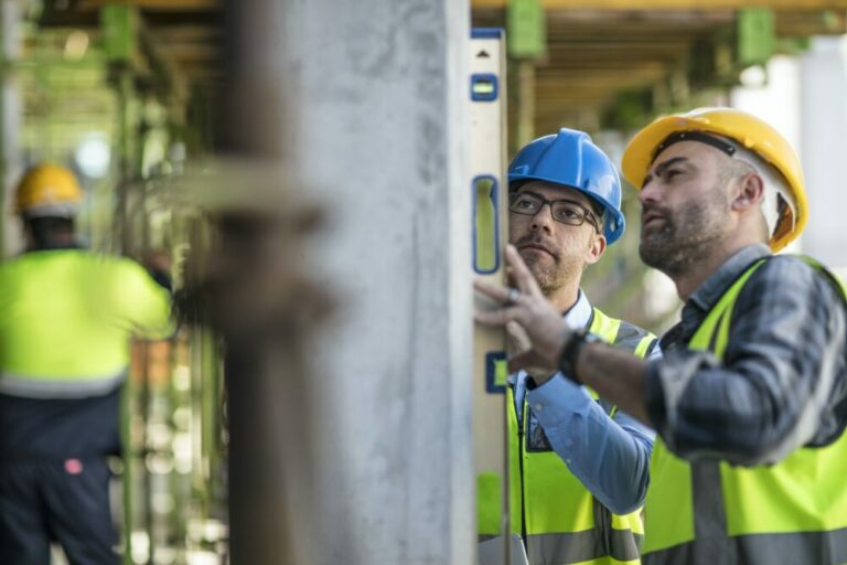 Project manager and construction worker using spirit level