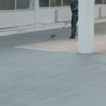 Worker paints the concrete floor with liquid gray paint