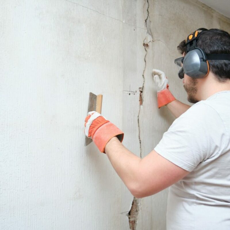 Construction worker repairing a crack, plastering cement on wall
