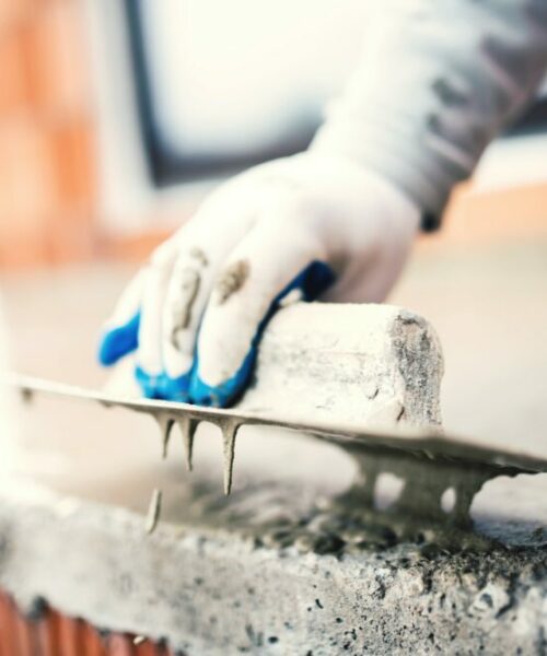 construction worker using steel trowel for plastering