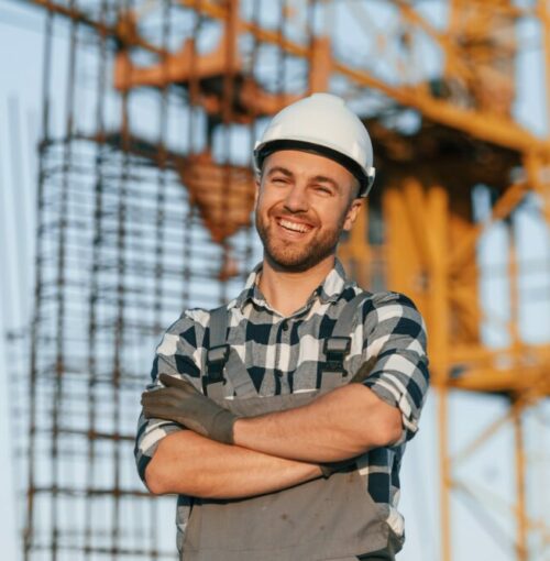 Happy worker is standing on the construction site at daytime